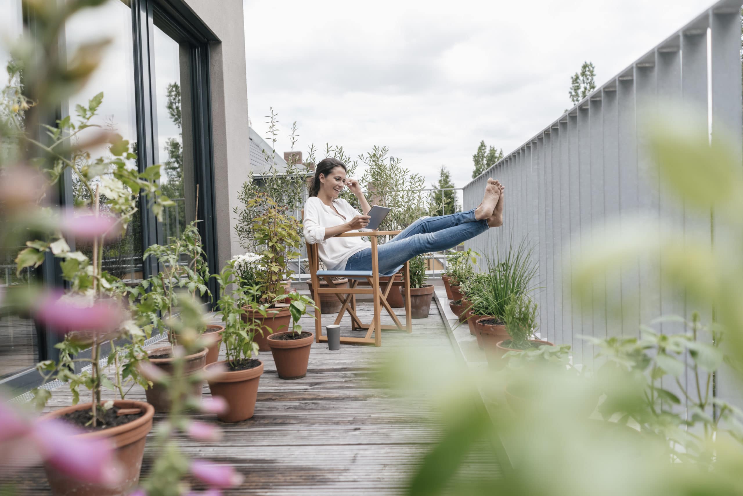 Young woman sitting outside on her porch watching videos on her tablet.